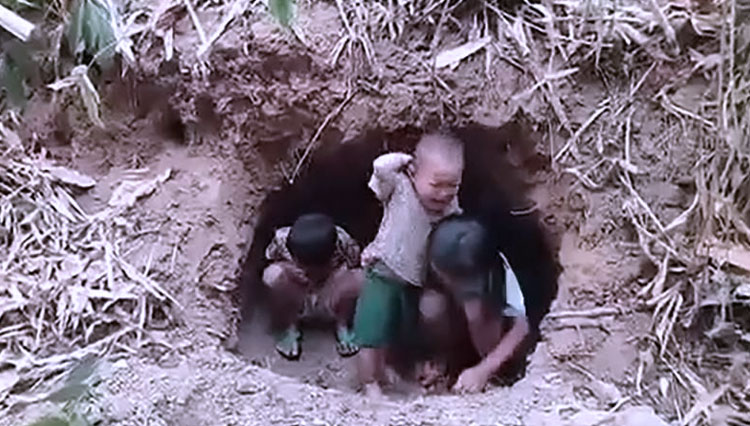 Anak-anak balita terlantar berlindung di lubang yang digali di hutan di distrik Pupun Myanmar dekat perbatasan dengan Thailand. (FOTO: Tangkapan layar video UGC/AFPTV)