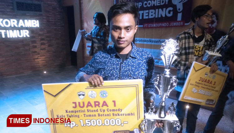 Pemenang kompetisi stand up comedy Kafe Tebing Jamil, memamerkan hadiah dan tropi juara 1. (Foto: Muhammad Faizin/TIMES Indonesia)