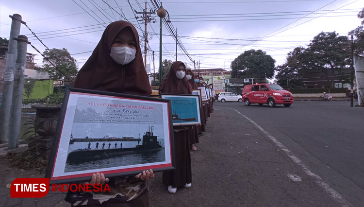 Pelajar MTsN 6 Malang membawa foto bingkai KRI Nanggala 402 dalam aksi doa dan pembagian bunga. (Foto: Binar Gumilang/TIMES Indonesia)