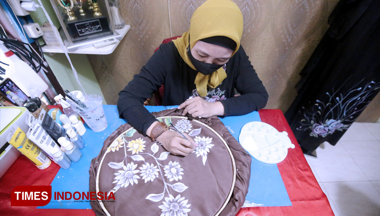 Catur Andriani saat mengerjakan proses melukis di atas jilbab. (FOTO: Humas Pemkot Surabaya for Times Indonesia) 