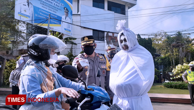 Anggota Lantas Polres Pacitan yang menyerupai pocong ikut sosialisasi prokes dan bagikan masker (FOTO: Rojihan/TIMES Indonesia)