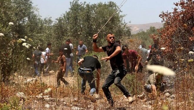 Pengunjuk rasa Palestina menggunakan ketapel untuk melemparkan batu ke pasukan keamanan Israel.Pasukan keamanan Israel menembakkan gas air mata untuk membubarkan pengunjuk rasa Palestina. (FOTO:Al Jazeera/AFP).