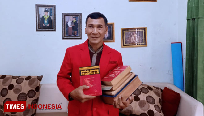Purbodjati, seorang dosen di Universitas Negeri Surabaya yang juga sebagai Dewan Pertimbangan DPC PA GMNI Magetan saat memegang buku koleksinya tentang Revolusi Indonesia. (Foto: Aditya Candra/TIMES Indonesia)