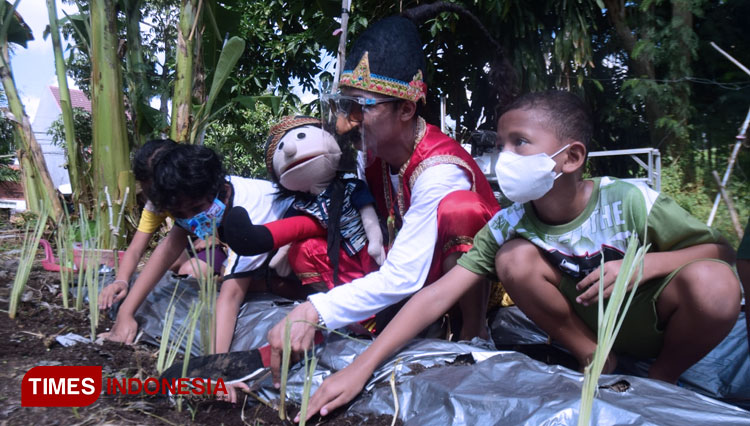Pendongeng Harris Riski saat mendongeng dihadapan anak-anak sambil menaman tanaman, Kamis (3/6/2021). (Foto: Khusnul Hasana/TIMES Indonesia). 