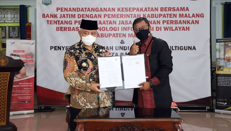 Bupati Malang Abah Sanusi ketika menunjukkan perjanjian kerjasama dengan Bank Jatim yang telah ditandatangani. (Foto : Humas Pemkab Malang).