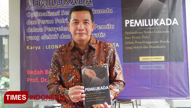 Leonardus Simarmata menunjukkan karya buku Pemilukada saat peluncuran sekaligus bedah buku. (Foto: Naufal Ardiansyah/TIMES Indonesia)