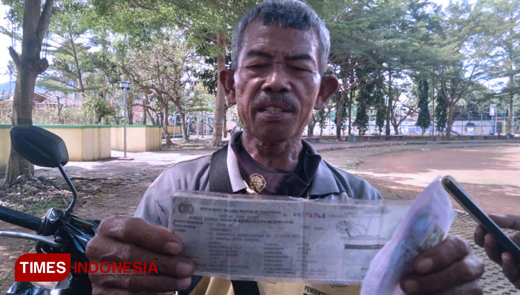 Didi menunjukkan STNK motor kredit macet yang didapatnya sebagai hadiah jalan santai (FOTO: Susi/TIMES Indonesia)