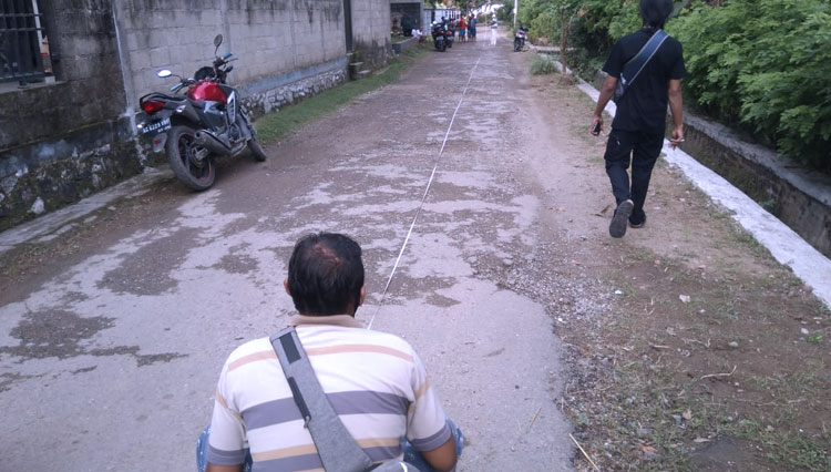 Tim Survei saat mengukur panjang jalan yang akan di bangun dan Kepala Desa Mentoro Rochman berbaju kaos orange (Foto: Yusuf For TIMES Indonesia)