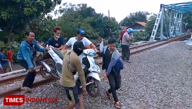 Kendaraan warga yang melintas di rel kereta, dengan digotong oleh masyarakat setempat.(Foto: Dede Sofiyah/TIMES Indonesia)