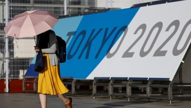 Seorang wanita berjalan melewati papan nama Olimpiade Tokyo 2020 di Pusat Pers Utama selama wabah penyakit virus corona (COVID-19) di Tokyo, Jepang, 16 Juli 2021.(FOTO: Reuters)