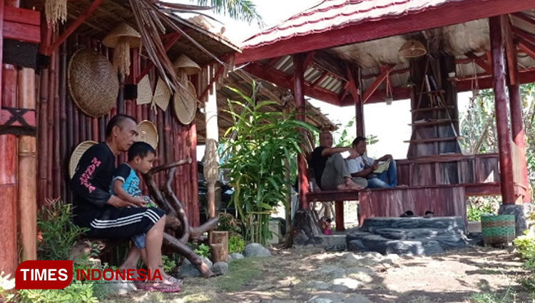 Seorang ayah sedang mengasuh anak dan beberapa orang warga tengah asik membaca di Saung Macakal Perumahan Kota Baru, Cibeureum, Kota Tasikmalaya, Minggu (18/7/21) petang (FOTO : Harniwan Obech/TIMES Indonesia)