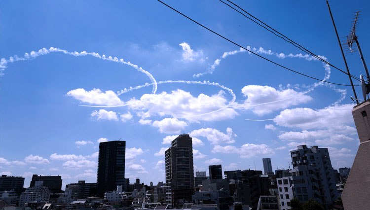 Tim aerobatik Blue Impulse Angkatan Udara Bela Diri menelusuri lima cincin Olimpiade di langit di atas Tokyo pada hari Rabu. (FOTO A:Japan Today/AP)