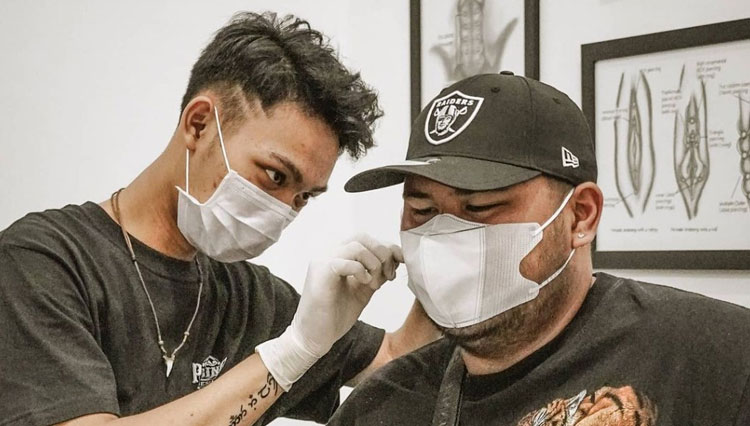 A guy pierce his ears at the professionals. (Photo: Freepik)