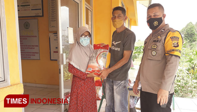 Lurah Hendi (tengah) didampingi Bhabinkamtibmas menyerahkan bantuan beras PPKM kepada salahseorang penerima di kantor Kelurahan Rebah Tinggi (Foto : Asnadi/Times Indonesia) 