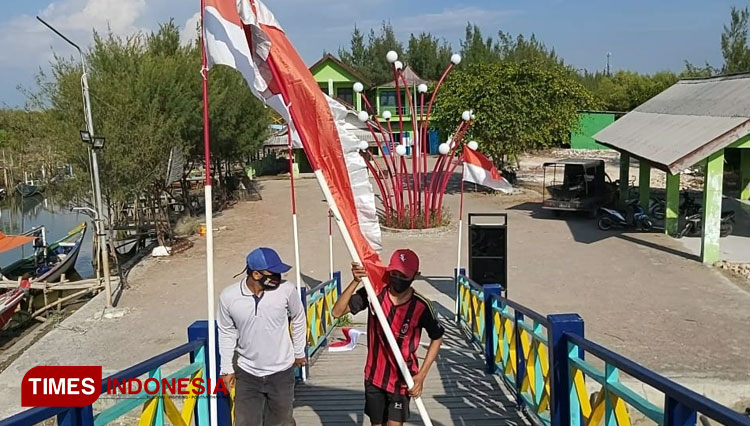 Nelayan saat mengibarkan bendera merah putih di atas perahu (Foto: Akmal/TIMES Indonesia).