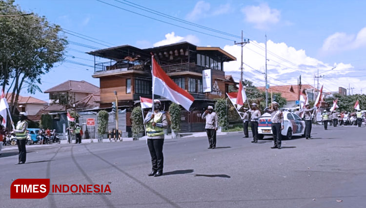 Anggota Polresta Banyuwangi mengibarkan bendera Merah Putih dan mengehentikan lalulintas disaat detik-detik proklamasi kemerdekaan Republik Indonesia. (FOTO: Agung Sedana/ TIMES Indonesia)