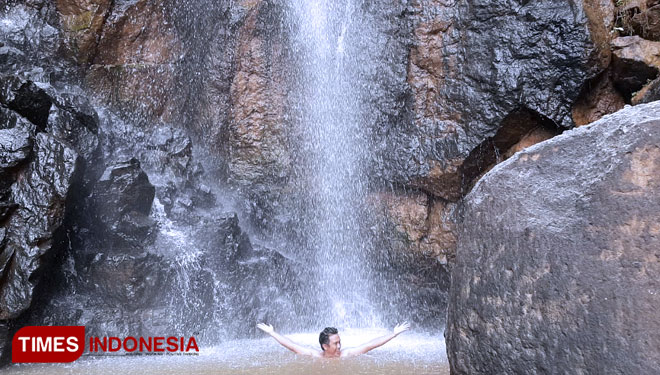 A visitor enjoying his time dipping his body under the Grojogan Jurug or Jurug Waterfall, Pacitan. (Photo: Rojihan/TIMES Indonesia)