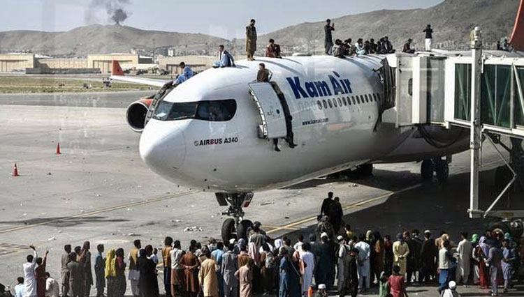 Orang-orang Afghanistan naik ke atas sebuah pesawat saat mereka menunggu di bandara Kabul (16/8/2021). Bandara internasional di Kabul dilanda kekacauan dan kemacetan lalu lintas yang parah. (FOTO: AFP)