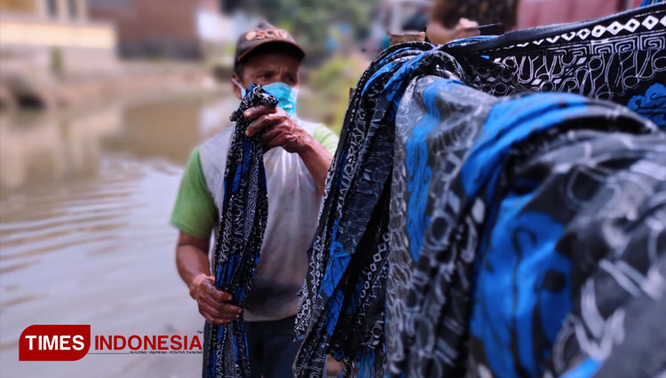 Seorang karyawan Galery Nanda Batik mengangkat beberapa helai kain batik setelah melakukan proses pencucian di workshop Galiry Nanda Batik, Kampung Batik Ciroyom Cigeureung, Cipedes, Kota Tasikmalaya, Jawa Barat. Sabtu (2/10/21) siang (FOTO: Harniwan Obec