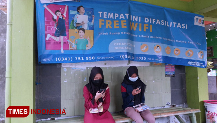 Dua pelajar asal Jl Bareng Tenes 4A saat melakukan pembelajaran daring dengan menggunakan layanan wifi gratis dari Diskominfo Kota Malang. (Foto: Rofi/TIMES Indonesia)