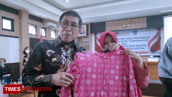 Perajin batik Ema Siti Asma menunjukkan produknya saat berfoto dengan Wali Kota Tasikmalaya H. M. Yusuf di Aula Balai Kota Tasikmalaya. (FOTO: Harniwan Obech/TIMES Indonesia)
