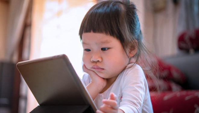 Illustration – A toddler playing with a gadget. (PHOTO: Khumthong/ Shutterstock)
