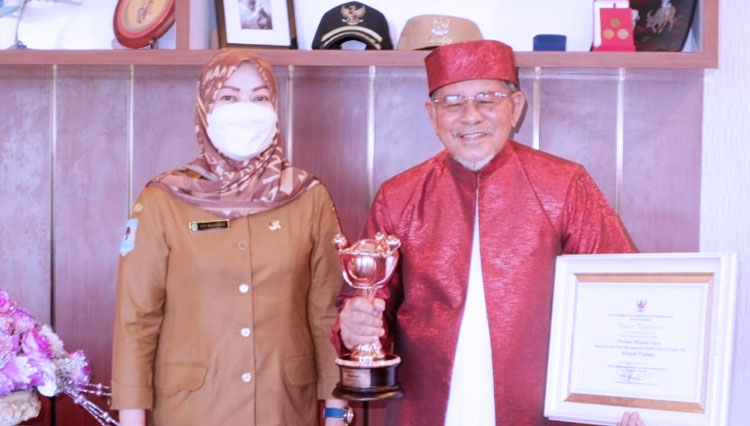 Gubernur KH Abdul Gani Kasuba bersama Kadis PPPA Musyrifah Alhadar pose bersama menunjukkan piala dan piagam penghargaan APE 2020. (Foto: Dinas PPPA Malut)