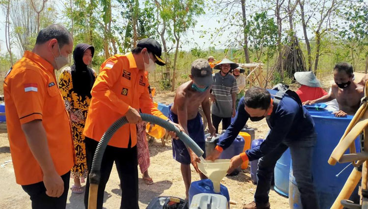 Kalaksa BPBD Jatim Drs Budi Santosa menyerahkan bantuan air bersih di lokasi kekeringan di Bangkalan, Kamis (21/10/2021). (Foto: Dok. BPBD Jatim) 