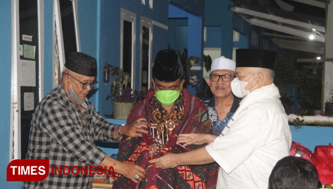 Ketua Umum LPTQ Sumut dan pembina kafilah STQ Nasional XXVI Sumut mengenakan kain kebanggaan sebagai kenang-kenangan.(Foto: Wahyudi Yahya/TIMES Indonesia).