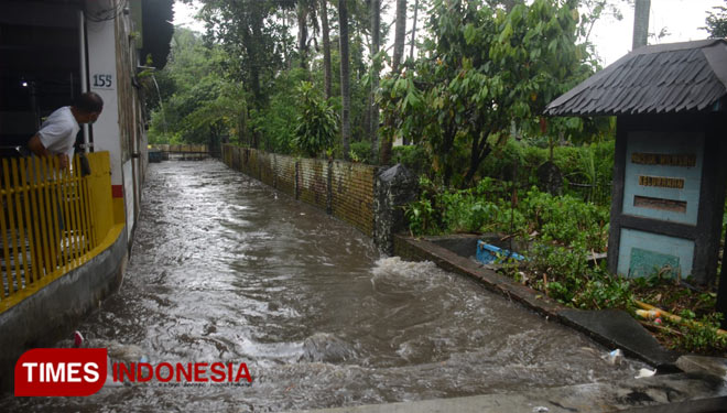 Seorang warga melihat kondisi selokan yang sudah tidak dapat menampung debit air di Kota Malang. (FOTO: Adhitya Hendra/TIMES Indonesia)