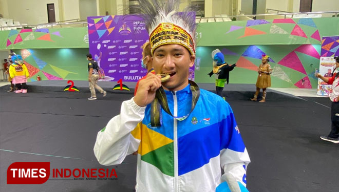 Hikmat atlet yang bernaung di bawah binaan NPCI Kabupaten Tasikmalaya menggigit medali emas sebagi bentuk kegembiraan setelah sukses meraih juara pada ajang Peparnas 2021 (FOTO: Dok. NPCI Kabupaten Tasikmalaya/TIMES Indonesia)