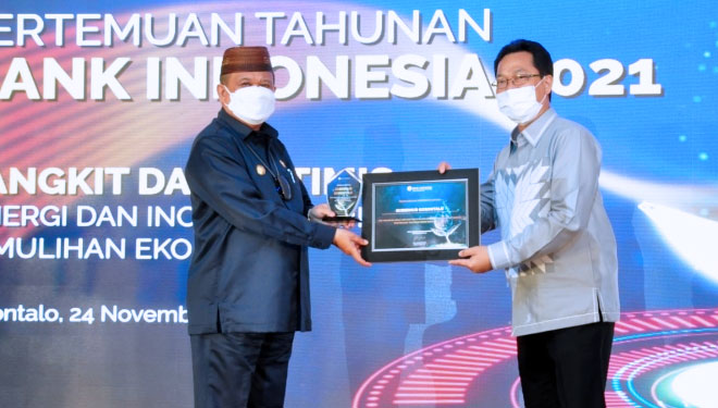 Wagub Gorontalo H. Idris Rahim (kiri) menerima penghargaan dari Kepala Perwakilan BI Gorontalo atas pencapaian jumlah merchat QRIS di wilayah Gorontalo yang melebihi target nasional pada Pertemuan Tahunan BI 2021. (Foto : Kominfotik Provinsi Gorontalo)