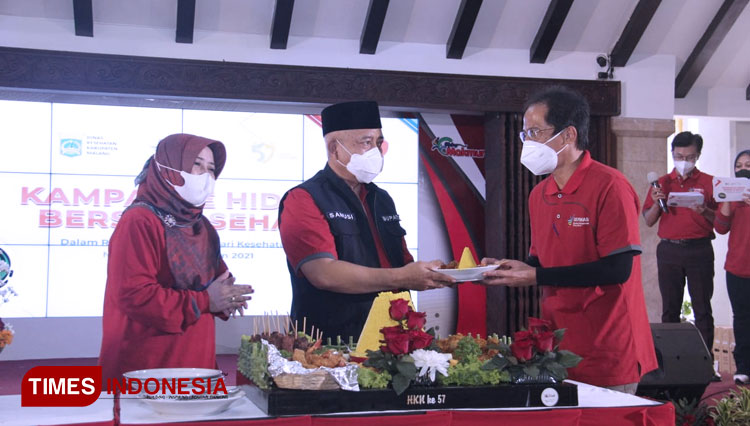 Bupati Malang Abah Sanusi ketika memberikan potongan tumpeng kepada Kepala Dinkes Kabupaten Malang drg Arbani Mukti Wibowo. (Foto: Binar Gumilang/TIMES Indonesia).
