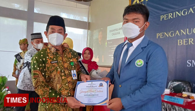 Kepala Dinas Pendidikan Kabupaten Banyuwangi, Suratno saat menyerahkan penghargaan kepada siswa-siswi berprestasi di SMP Bustanul Makmur Banyuwangi. (FOTO: Riswan Efendi/TIMES Indonesia)