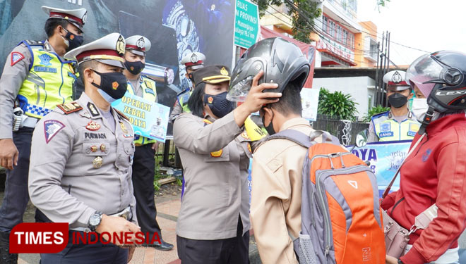 Kapolres didampingi Kasat lantas tampak memakaikan helm kepada siswa yang kedapatan tidak memakai helm (foto:Susi/TIMES Indonesia)