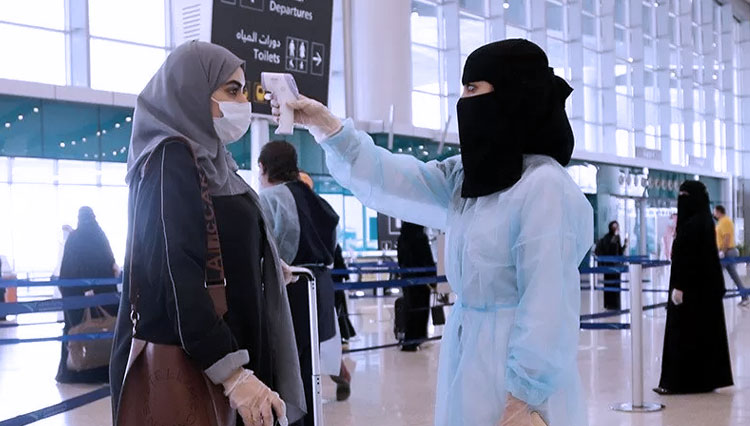 Petugas memeriksa suhu badan seorang perempuan yang baru tiba di Bandara King Abdul Aziz Jeddah, Arab Saudi. Pemerintah Arab Saudi mulai 1 Desember mengizinkan warga Indonesia masuk ke negara tersebut. (ANTARA/REUTERS/Ahmed Yosri)
