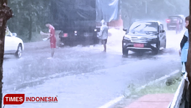 Nampak para pemuda warga Cikadu turun ke Jalan di Kawasan belokan Singaperbangsa yang selalu digenangi air saat hujan deras. (Foto: Susi/TIMES Indonesia)