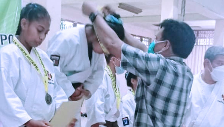 Ketum Pengkab PERKMI Sumba Timur NTT Djunaidi Bin Garib saat mengalungkan medali ke salha satu peserta kejuaraan Shorinji Kempo antar pelajar SMP-SMA ke-III se=NTT. (FOTO; Sekretariat PERKEMI Sumba Timur)