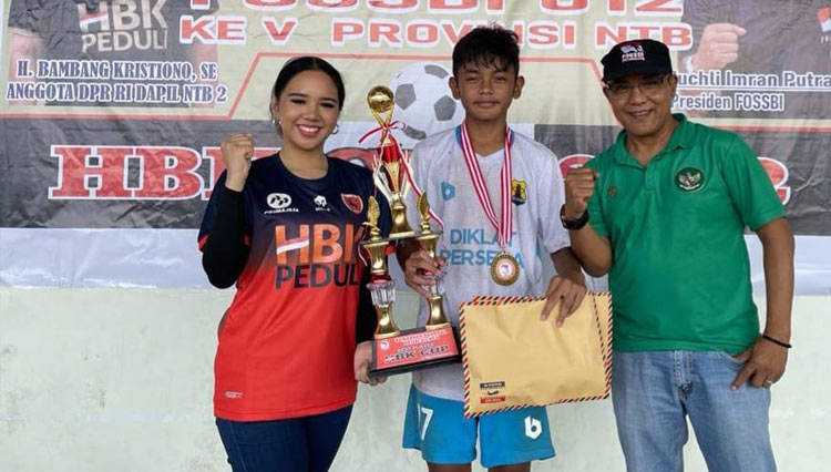 Sekretaris Yayasan HBK Peduli Rannya Agustyra Kristiono saat menyerahkan tropi pemenang kejuaraan nasional sepakbola U-12 di GOR 17 Desember.(Foto: HBK Peduli)