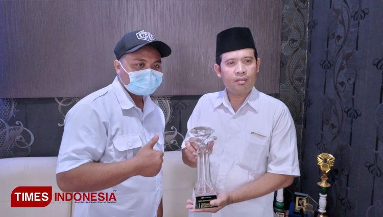 Sekdes Tamansuruh bersama Kadus Mondoluko memamerkan Trophy penghargaan Desa Cantik (Foto: Hafid Nurhabibi/TIMES Indonesia)