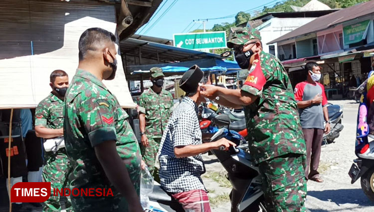 Salah seorang personel Koramil 07/Babahrot memakaikan masker untuk pengguna jalan (FOTO: T. Khairul Rahmat Hidayat/TIMES Indonesia)