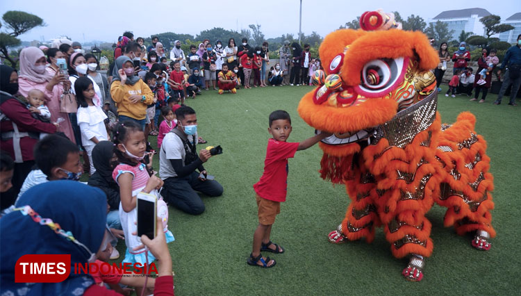 Seorang pengunjung anak di Matos memberi angpao kepada pemain barongsai di Twilight Zone Matos. (FOTO: Adhitya Hendra/TIMES Indonesia)